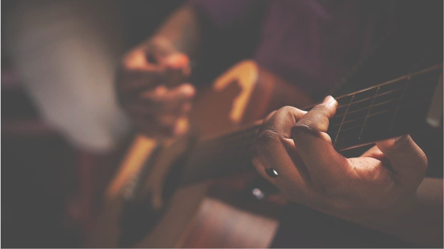 Close-up of hands playing acoustic guitar in warm, low light
